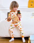 Child wearing Pumpkin Tractors long two-piece pajamas while holding a plush toy.