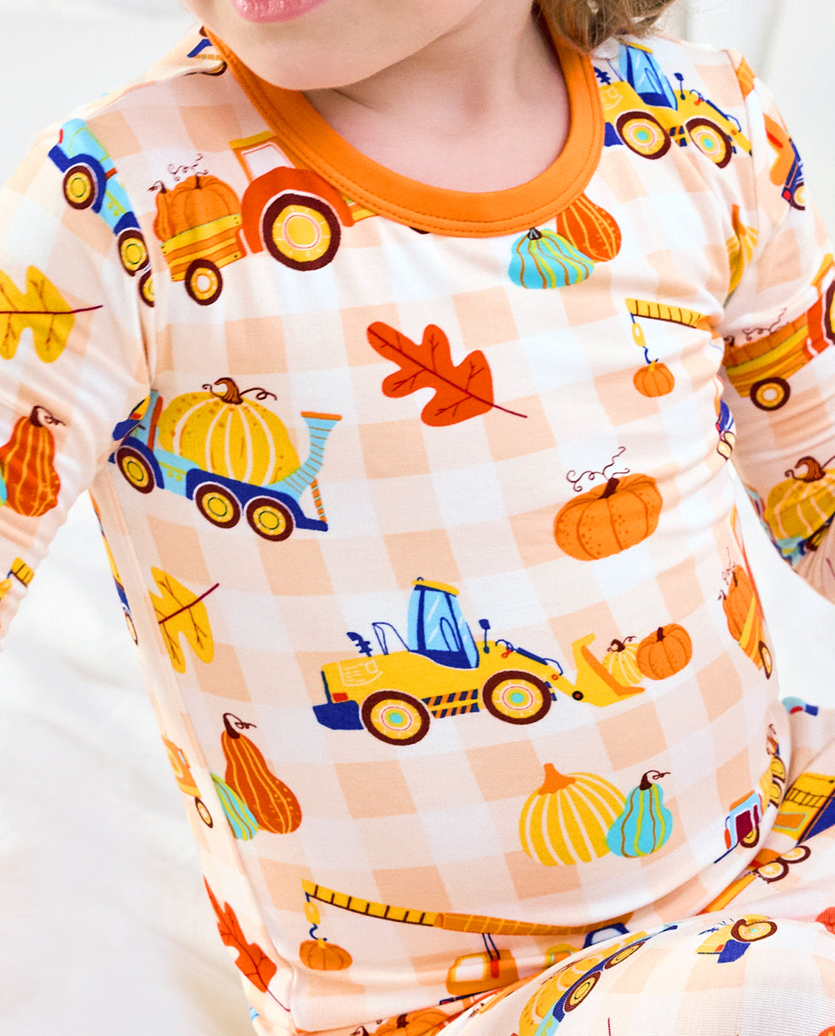 Close-up of Pumpkin Tractors long two-piece pajamas with construction vehicles, pumpkins, and autumn leaves.