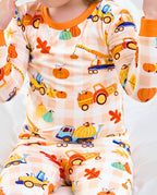 Close-up of Pumpkin Tractors long two-piece pajamas with orange trim and illustrated vehicles and pumpkins.