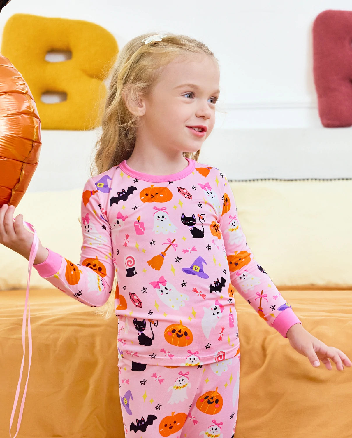 Spooky Cute Long Two-Piece Pajama Set - child wearing the pink Halloween pajamas while holding a balloon
