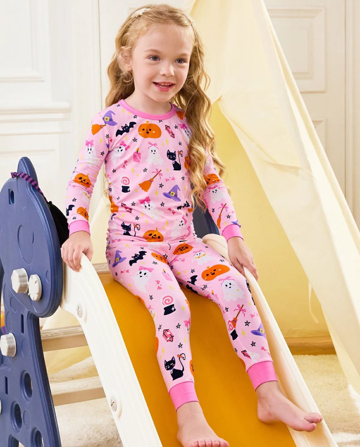 Spooky Cute Long Two-Piece Pajama Set - child wearing the pink Halloween pajamas while seated on a slide
