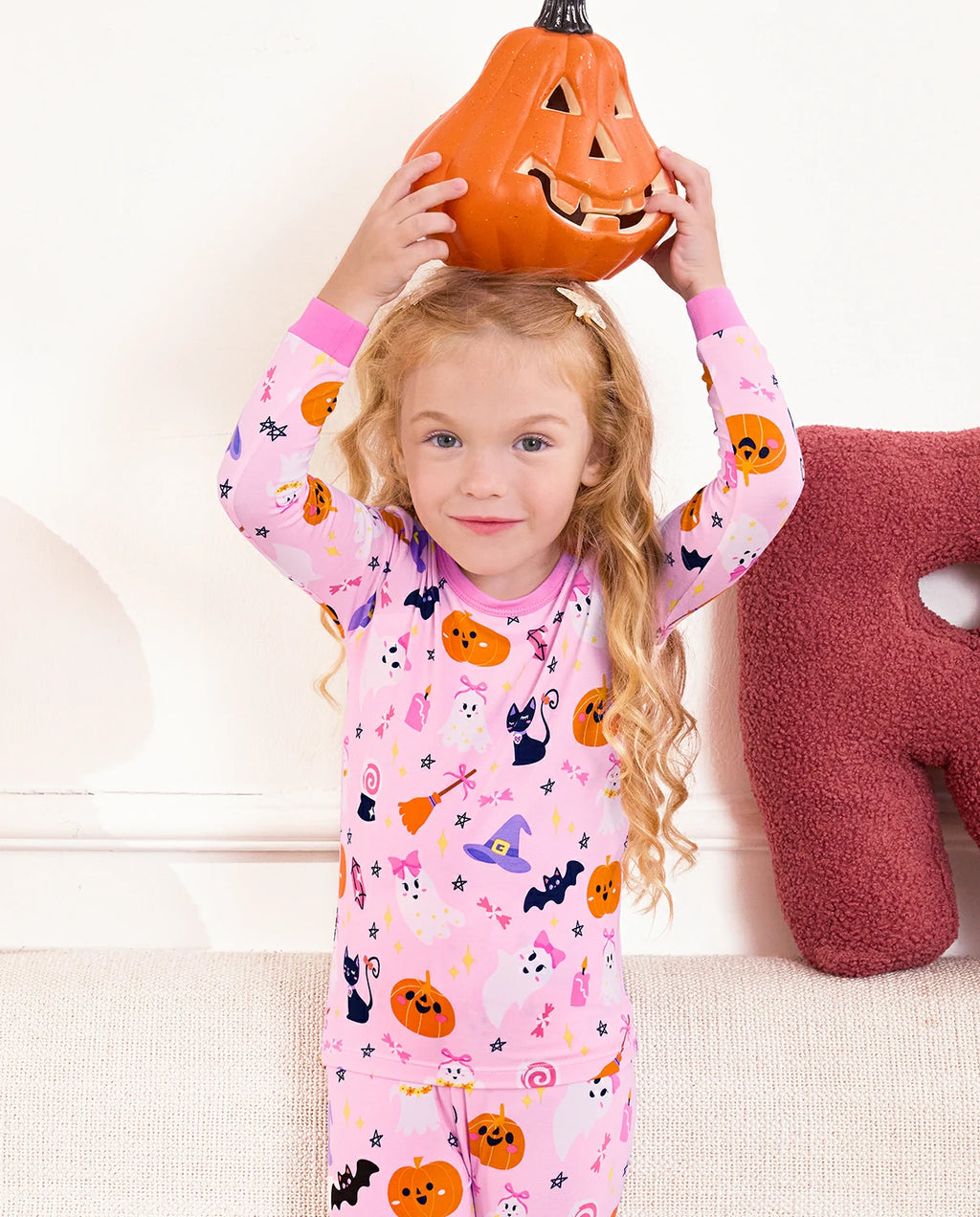 Spooky Cute Long Two-Piece Pajama Set - child holding a pumpkin bucket above their head while wearing the pajamas