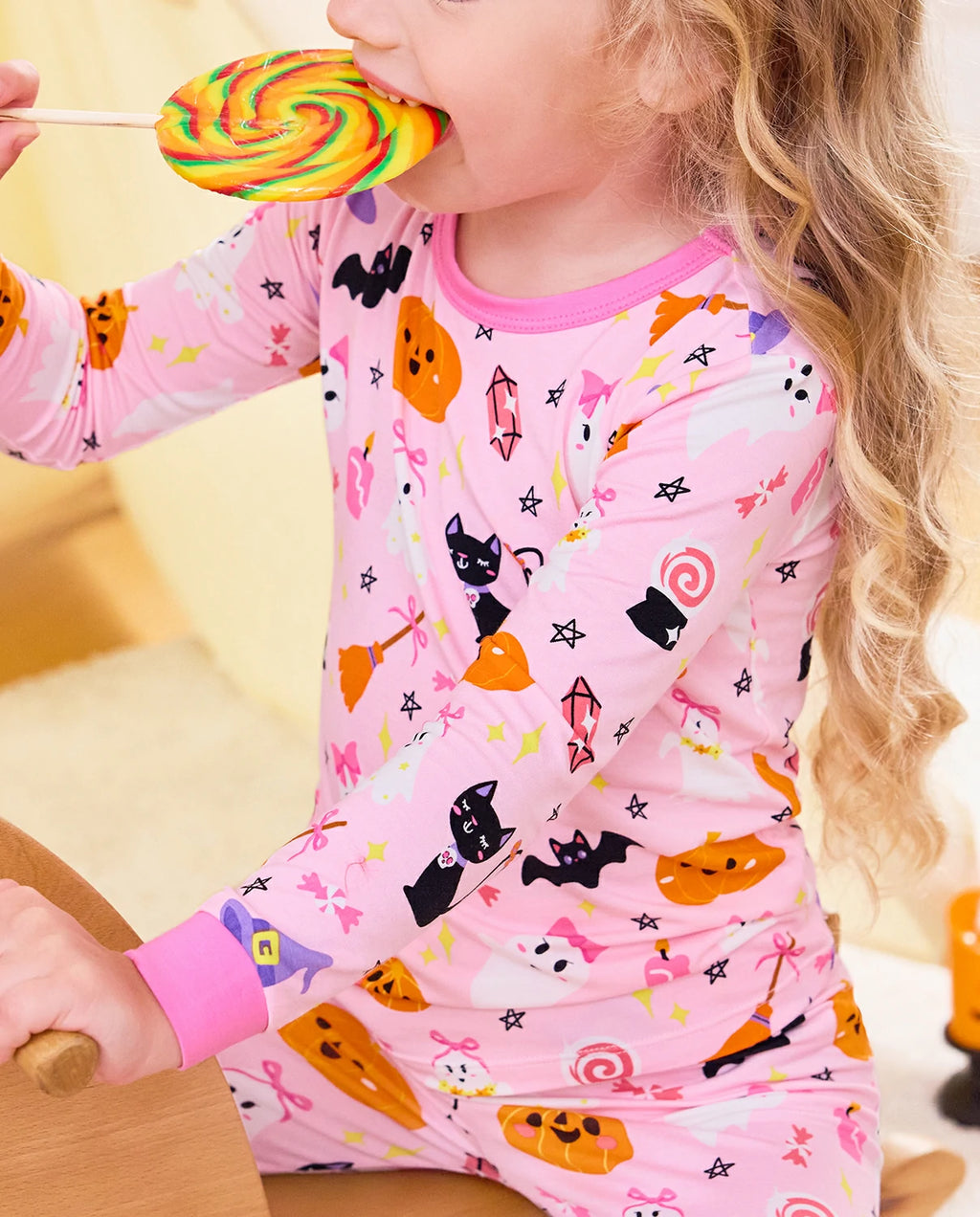 Spooky Cute Long Two-Piece Pajama Set - close-up of the Halloween print while the child holds a lollipop