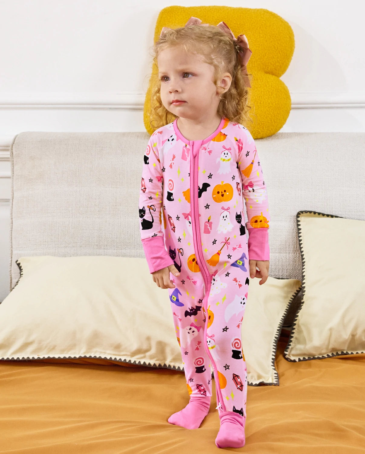 Spooky Cute Bamboo Zippy baby pajamas with pink Halloween ghost and pumpkin print in a cozy bedroom setting