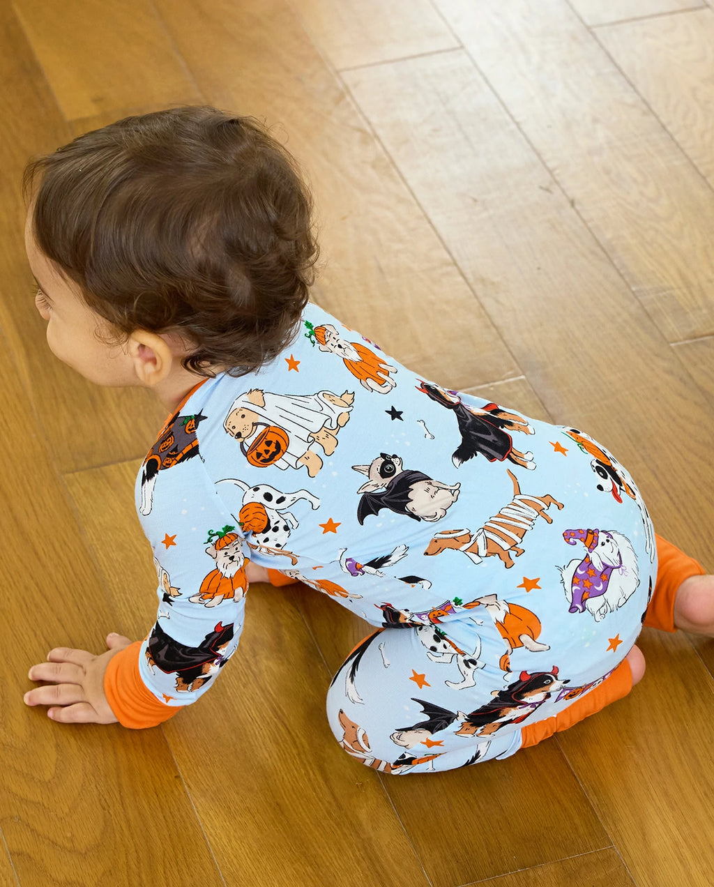 Baby crawling in Spooky Pups Bamboo Zippy on wooden floor