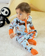 Baby sitting in Spooky Pups Bamboo Zippy with Halloween plush toy nearby