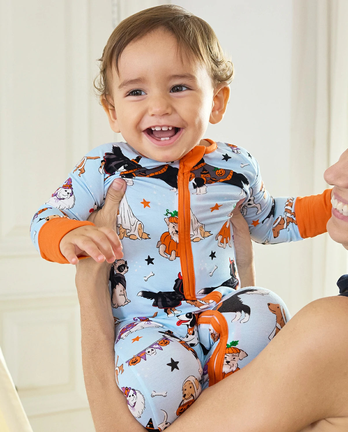 Smiling baby wearing Spooky Pups Bamboo Zippy with orange zipper