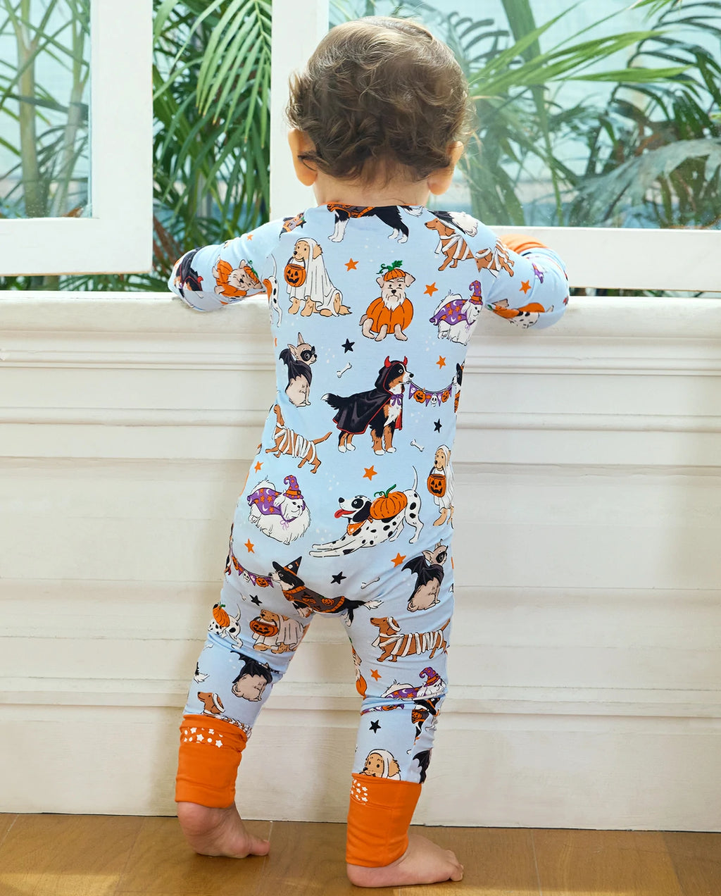 Back view of baby wearing Spooky Pups Bamboo Zippy by window