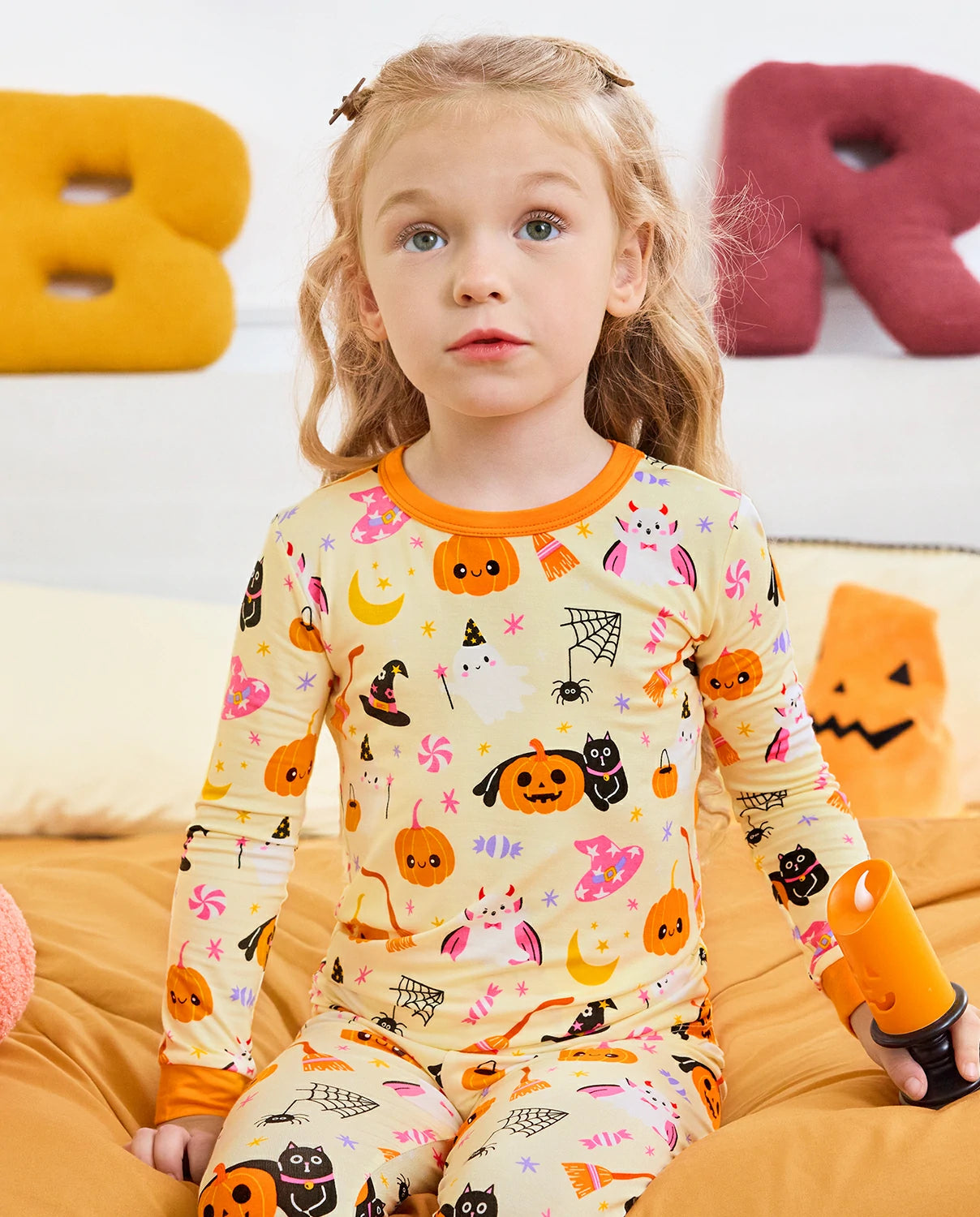 Spooky Sweet Long Two-Piece Pajama Set - child wearing the pajamas while seated on a bed