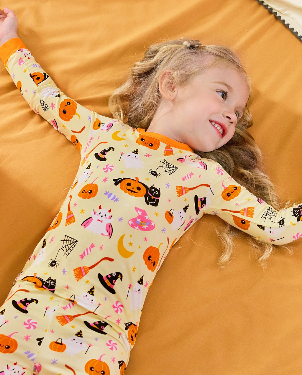 Spooky Sweet Long Two-Piece Pajama Set - child wearing the pajamas while reclining on a bed