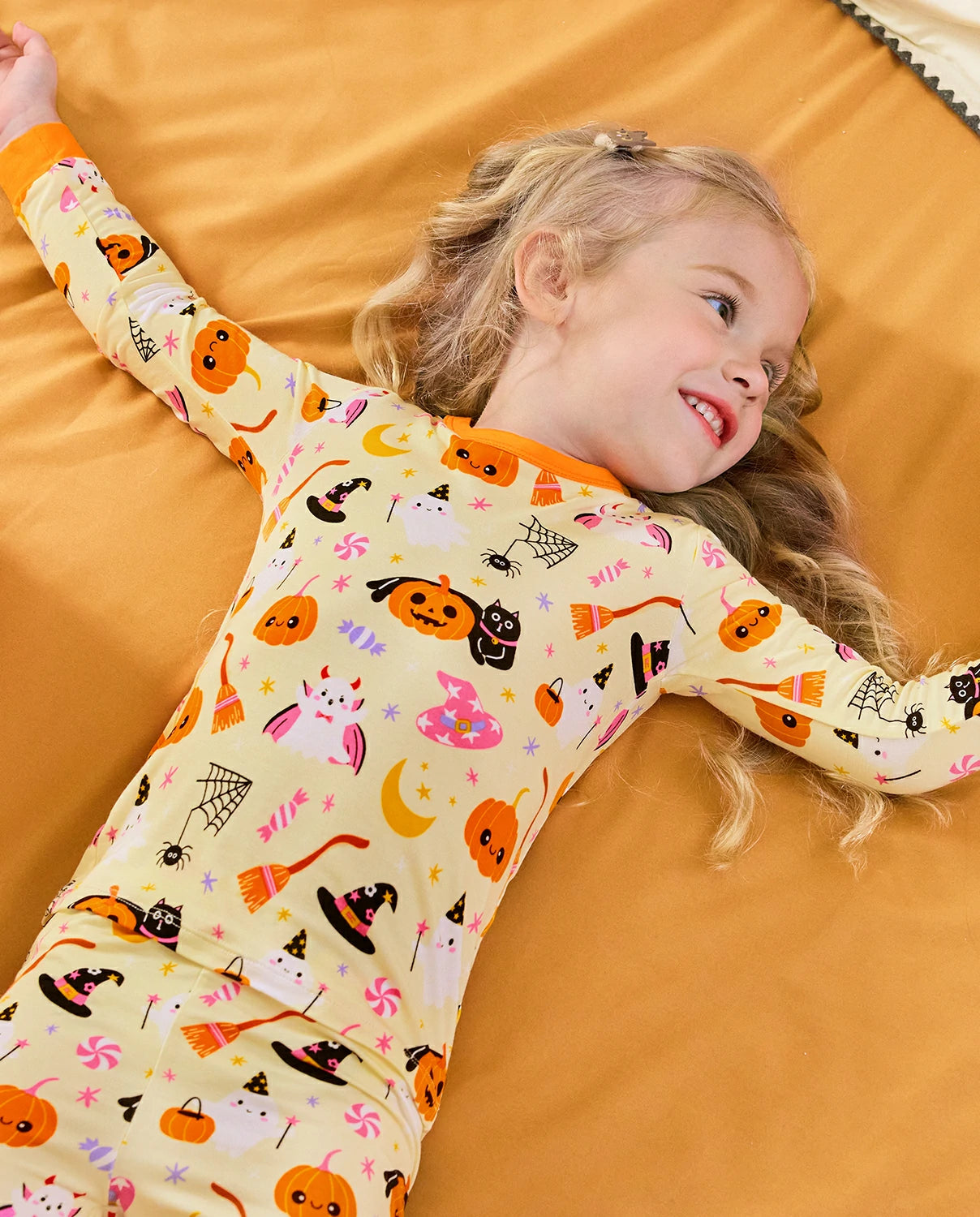 Spooky Sweet Long Two-Piece Pajama Set - child wearing the pajamas while reclining on a bed
