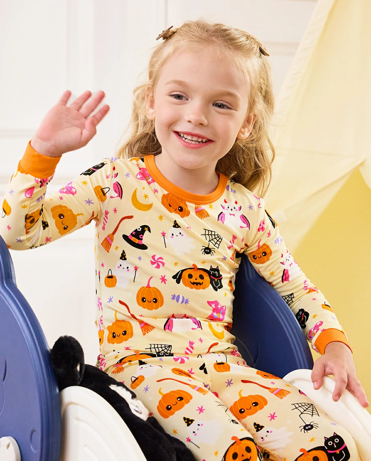 Spooky Sweet Long Two-Piece Pajama Set - child wearing the pajamas while seated on a slide and waving