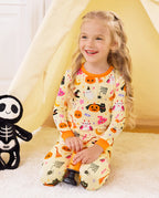 Spooky Sweet Long Two-Piece Pajama Set - child wearing the pajamas while seated beside a skeleton toy