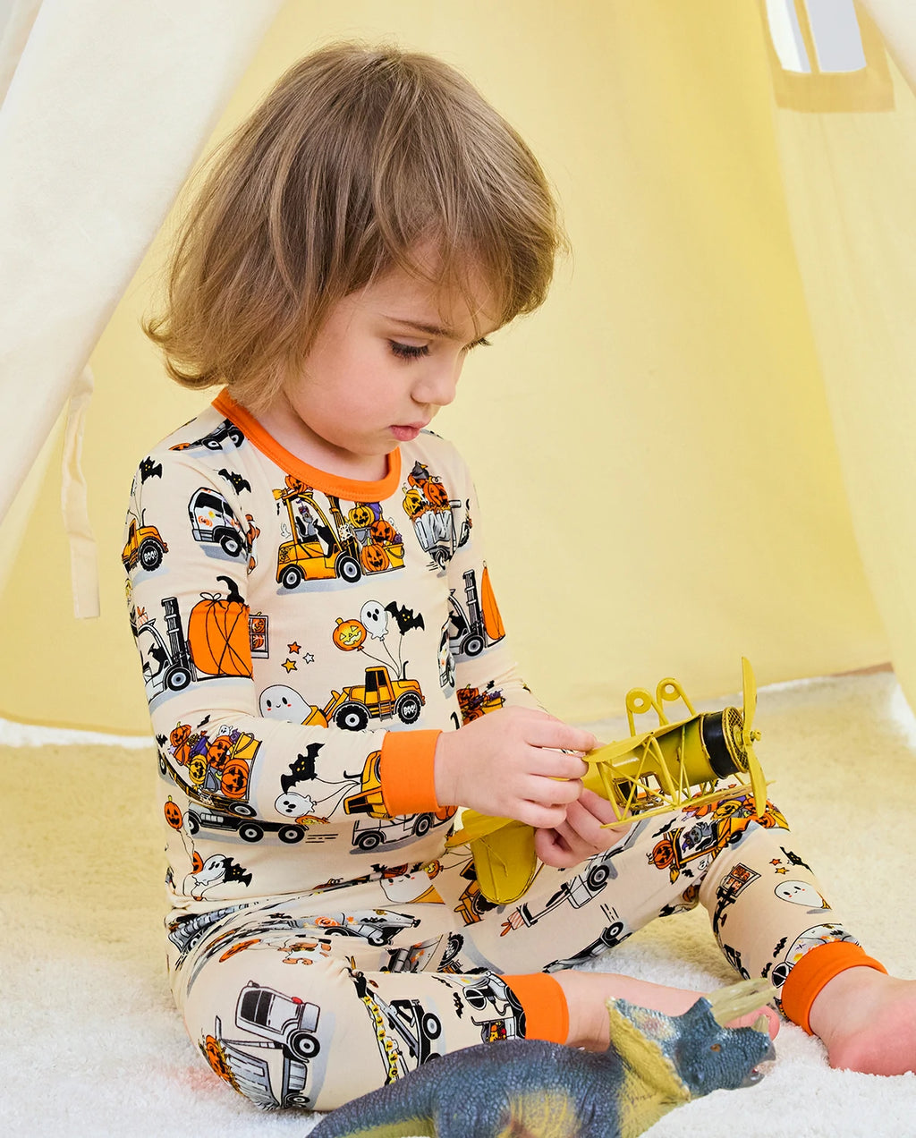 Trick Trucks Long Two-Piece Pajama Set - child wearing the pajamas while seated with toy trucks