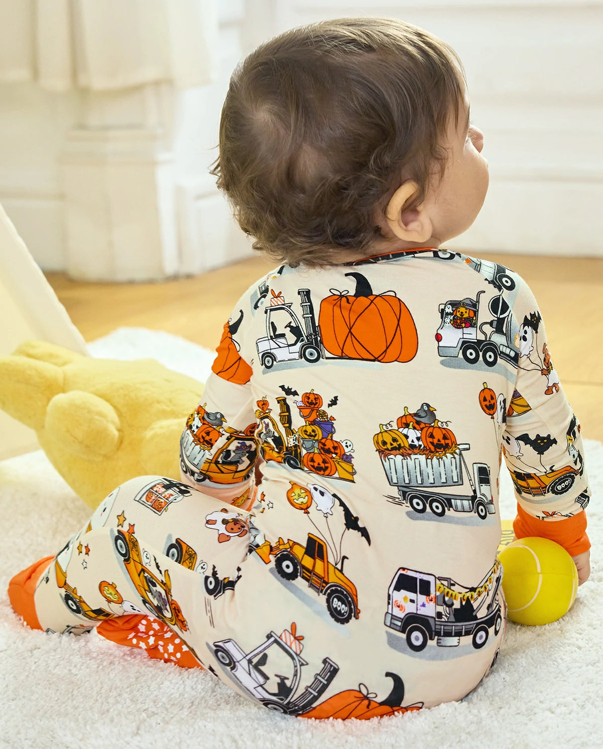 Baby sitting in Trick Trucks bamboo zippy with Halloween truck and pumpkin print