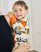 Smiling baby in Trick Trucks bamboo zippy held by caregiver