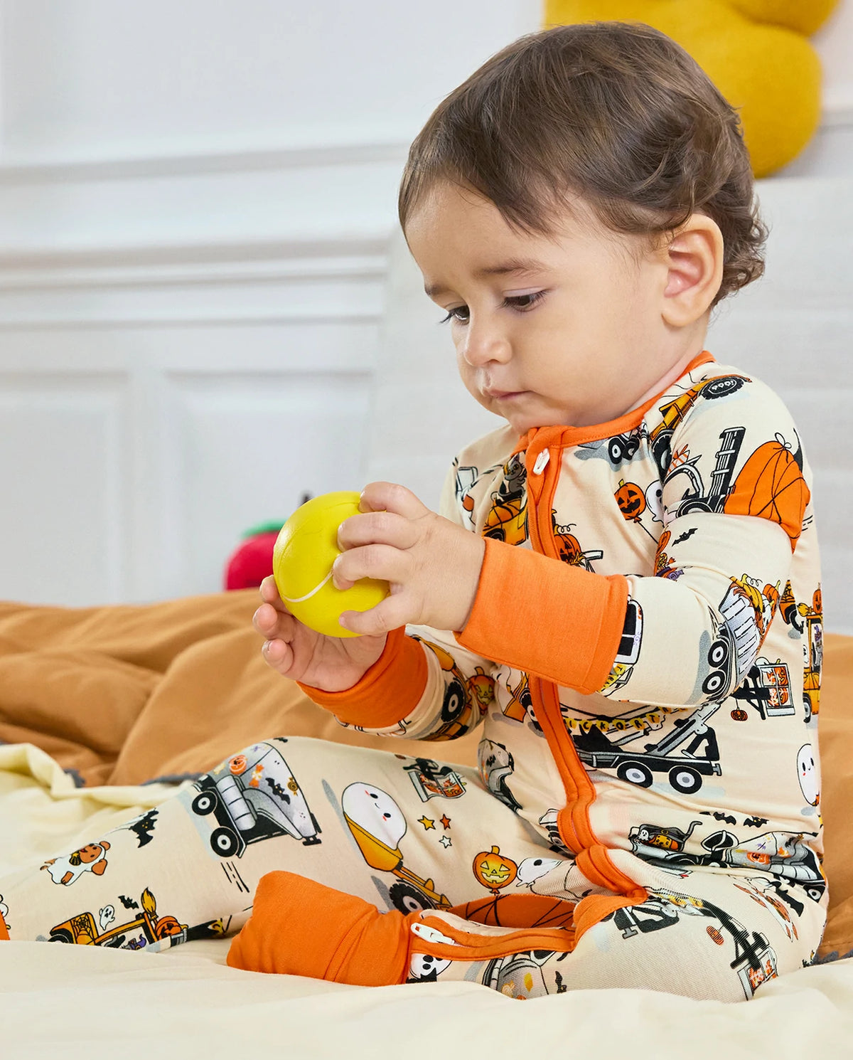 Baby sitting in Trick Trucks bamboo zippy and holding a yellow ball
