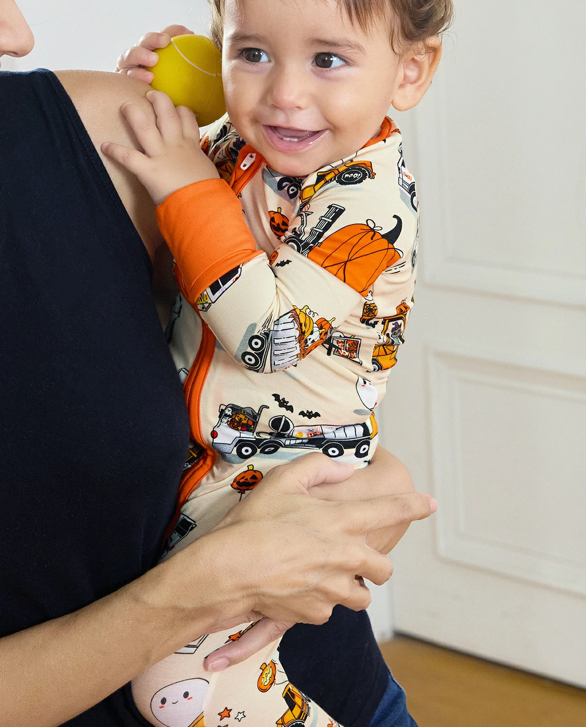 Smiling baby in Halloween truck bamboo zippy cuddling with caregiver