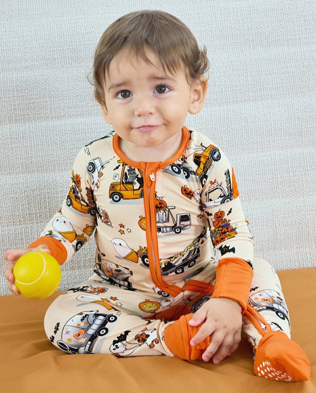 Baby sitting in Trick Trucks bamboo zippy with two-way zipper and orange footies